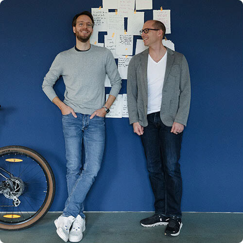 Sebastian and Steffen, two man stand near blue color wall, bicycle